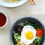 Korean rice bowl with beef, vegetables and egg in a stone pot