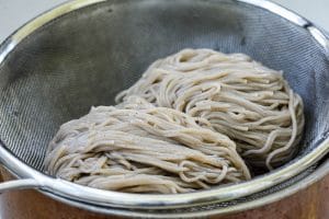 two mounds of cooked buckwheat noodles in a strainer