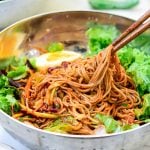 Cold buckwheat noodles and vegetables mixed in a spicy gochujang sauce