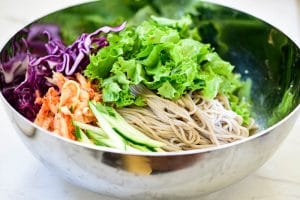 arranging julienned vegetables on top of buckwheat noodles