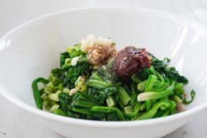 Blanched and squeezed spinach being mixed with Korean seasoning