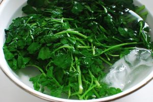 rinsing blanched watercress in cold water