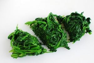 Blanched and squeezed watercress being cut into small pieces