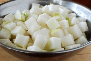 Cubed Korean radish being salted in a large bowl