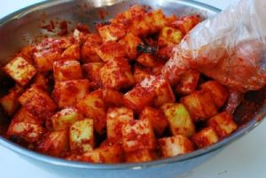 mixing salted cubed radish with kimchi seasonings