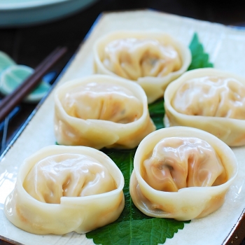 5 Kimchi dumplings on a square plate with a dipping sauce