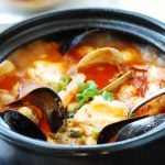 red spicy extra tofu stew with an assortment of seafood in an earthen pot