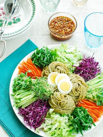 Cold noodles with vegetables and boiled egg slices in a large platter served with a sauce