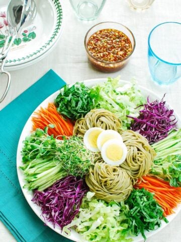 Cold noodles with vegetables and boiled egg slices in a large platter served with a sauce