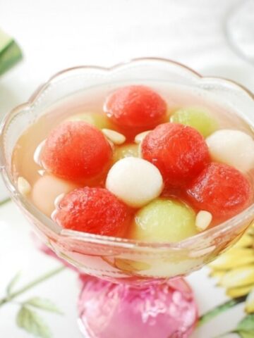 a Korean punch drink with watermelon and rice cake balls in a glass bowl