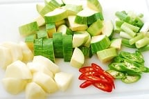 cutting zucchini and potato in cubes and thinly slicing a red chili pepper