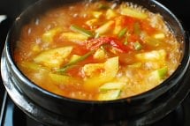 Boiling Korean stew with Potato and zucchini in red spicy gochujang broth in an earthenware