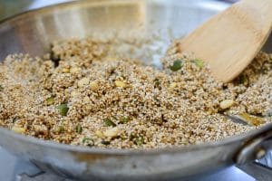 Sesame seeds, pumpkin seeds and pine nuts being mixed with a syrup in a pan