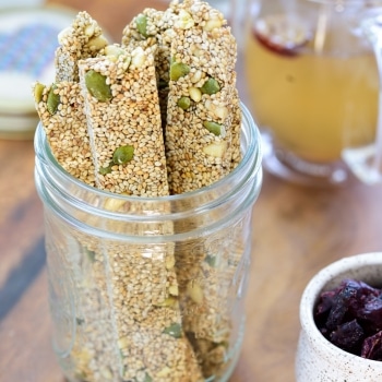 Long sticks of sesame crunch in a small mason jar with dried fruit snack and a cup of tea