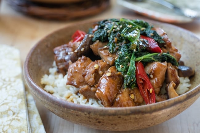 Chicken stir fry with kale and mushrooms in a brown ceramic bowl