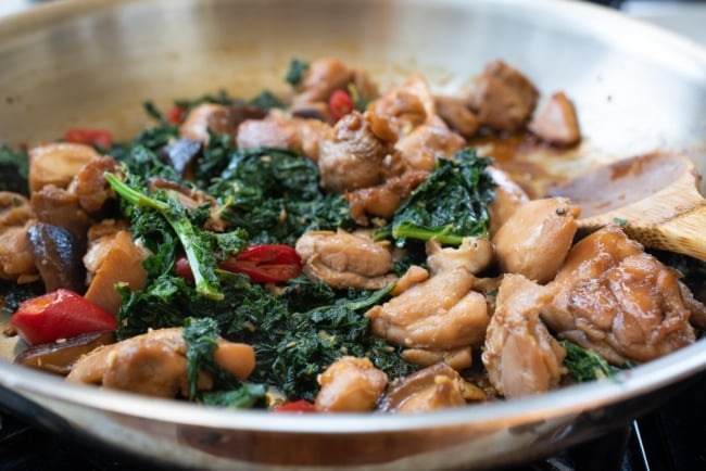 Stir frying chicken, kale and mushrooms in a pan