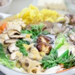 Korean hot pot with an assortment of mushrooms and other veggies in a shallow white pot