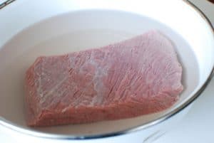 Beef brisket being soaked in water