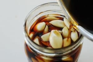 Korean pickled garlic in a jar with a soy brine