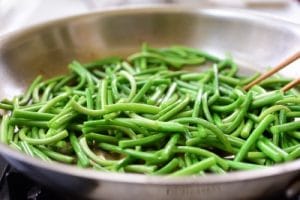 stir-frying garlic scapes in a pan