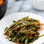 Korean garlic chive kimchi in a small plate served with a bowl of rice