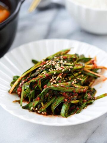Korean garlic chive kimchi in a small plate served with a bowl of rice
