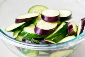 Salting eggplant and zucchini slices in a bowl