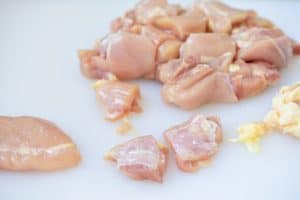 Cutting boneless, skinless chicken thighs into bite sized pieces