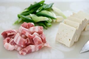 Cutting Pork, tofu, and scallions on a cutting board