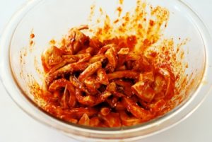 squid being mixed with a red spicy sauce