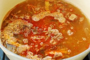 Red spicy soup in a large pot with shredded beef