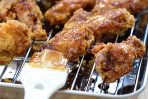 brushing soy garlic sauce on fried chicken wings