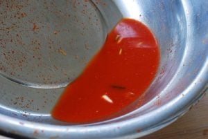 rinsing a large bowl with leftover kimchi seasoning for kimchi liquid