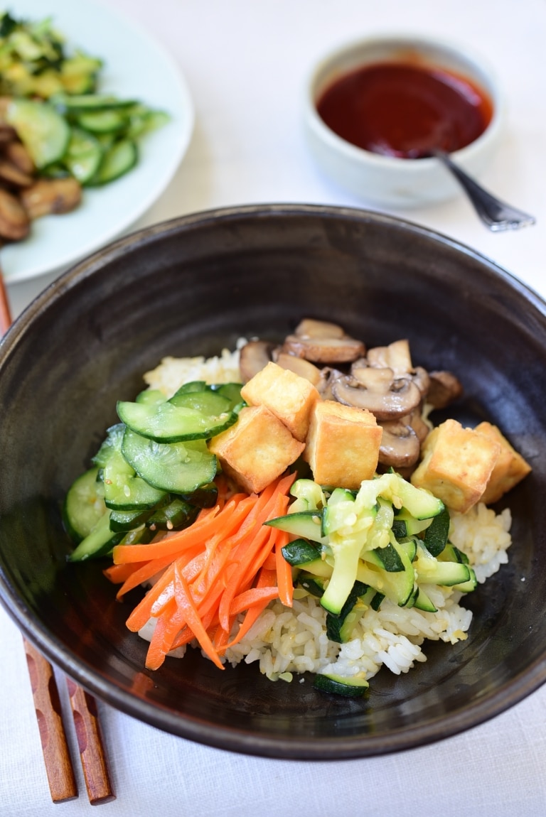 Tofu bibimbap in a large bowl with gochujang sauce