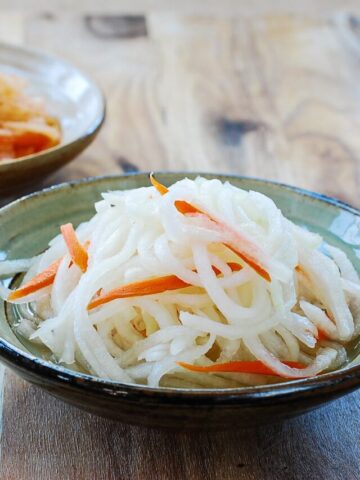 Sweet and sour julienned radish salads in two bowls (white and orange color)
