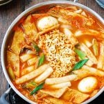 Korean spicy rice cakes with fish cake, boiled eggs and ramen noodles in the middle in a shallow pot