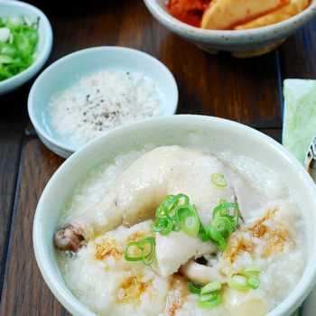 Chicken leg on top of rice porridge served with kimchi