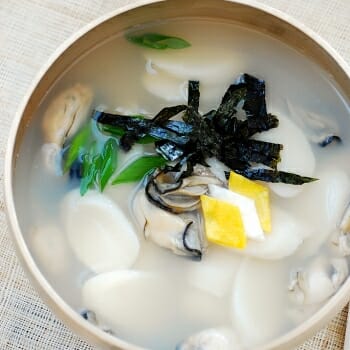 Korean rice cake soup made with oysters garnished with eggs and seaweed sheet