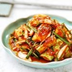 Cucumber kimchi in a plate with chopsticks in the background