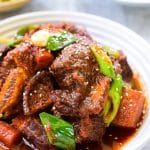 Red spicy braised short ribs with vegetables in a white plate