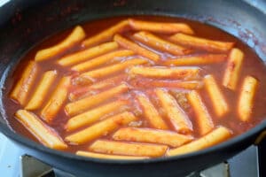 Boiling rice cakes in a spicy broth in a large pan