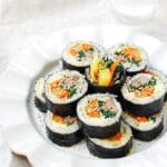 sliced kimbap stacked up on a plate with the end piece in the middle