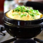 Korean steamed eggs being cooked in an earthenware pot on the stovetop