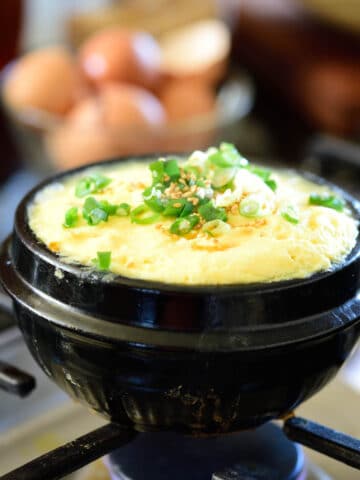 Korean steamed eggs being cooked in an earthenware pot on the stovetop