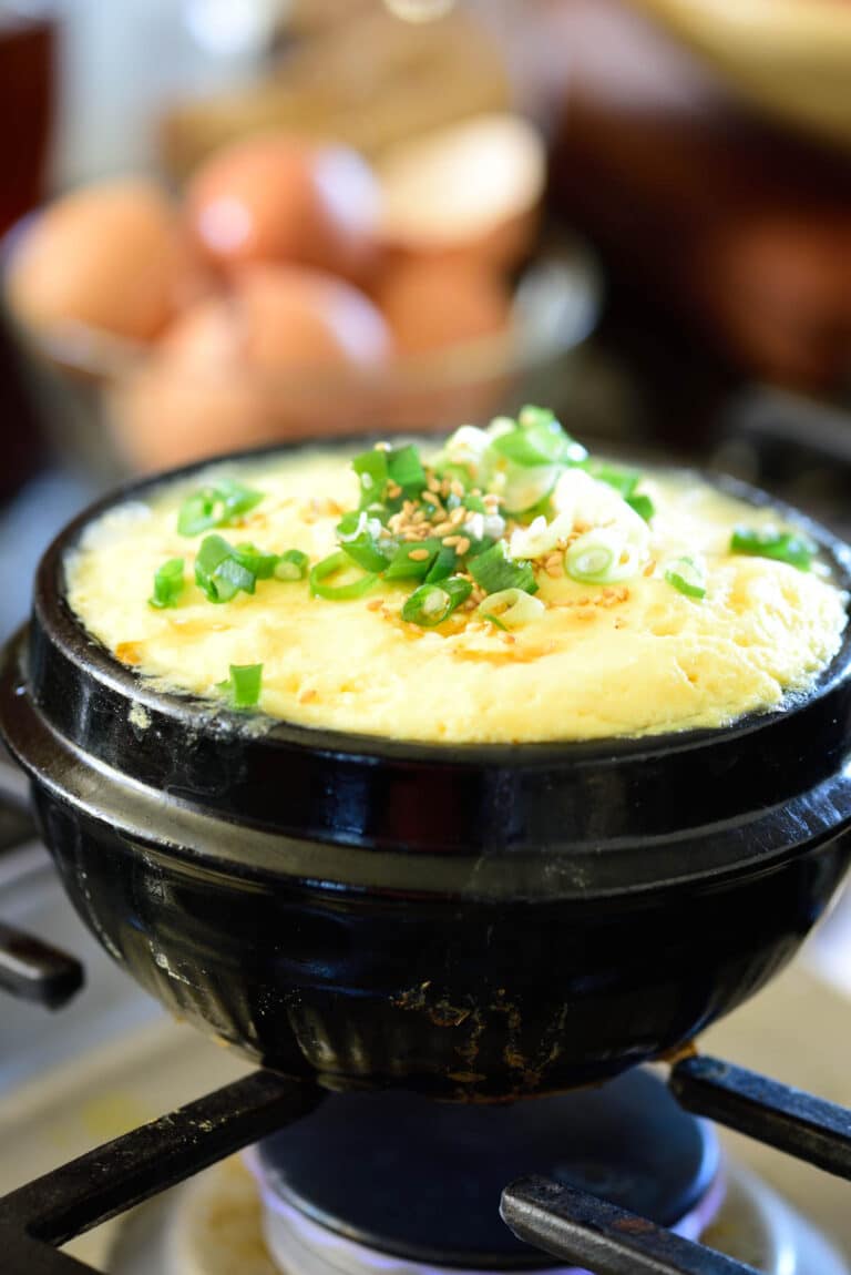 Korean steamed eggs being cooked in an earthenware pot on the stovetop