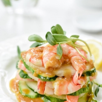 Shrimp salad stacked up on a plate with mustard dressing