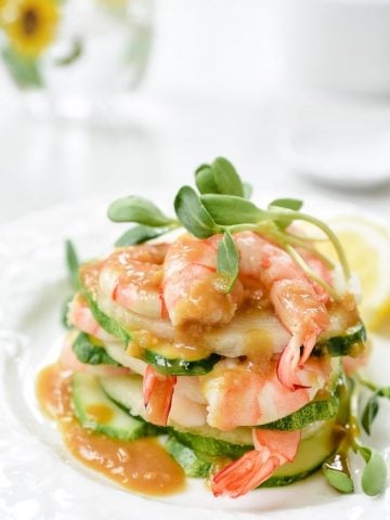 Shrimp salad stacked up on a plate with mustard dressing