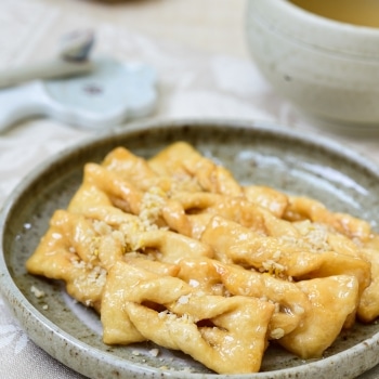 Korean twisted ginger cookies topped with chopped pine nuts with a cup of tea