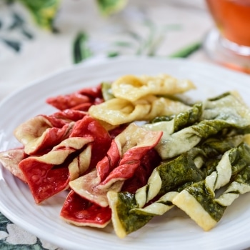Korean twisted ginger cookies in red, green and white with a glass cup of tea on Christmas background