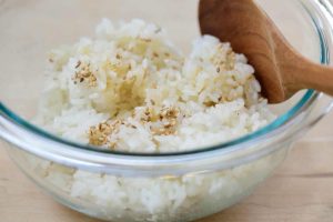 Mixing cooked rice with sesame oil, salt and sesame seeds